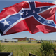 Confederate flag supporters fly their flags across the street from Durant High School, where President Barack Obama will be speaking, in Durant, Okla., Wednesday, July 15, 2015.